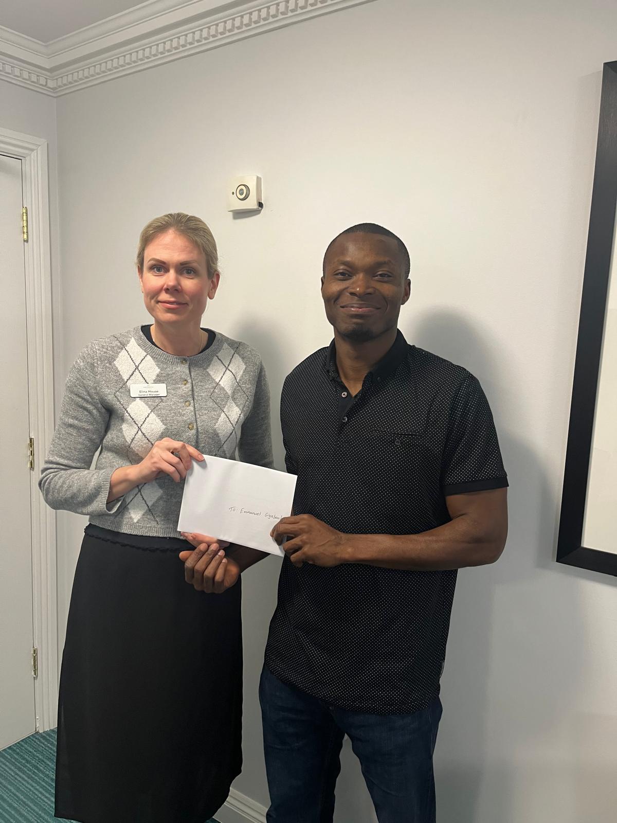 Registered Nurse Emmanuel accepts the £100 voucher presented by General Manager Elina House