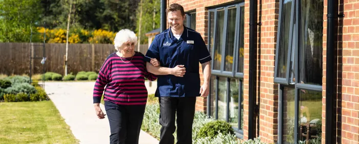 Resident and carer linking arms