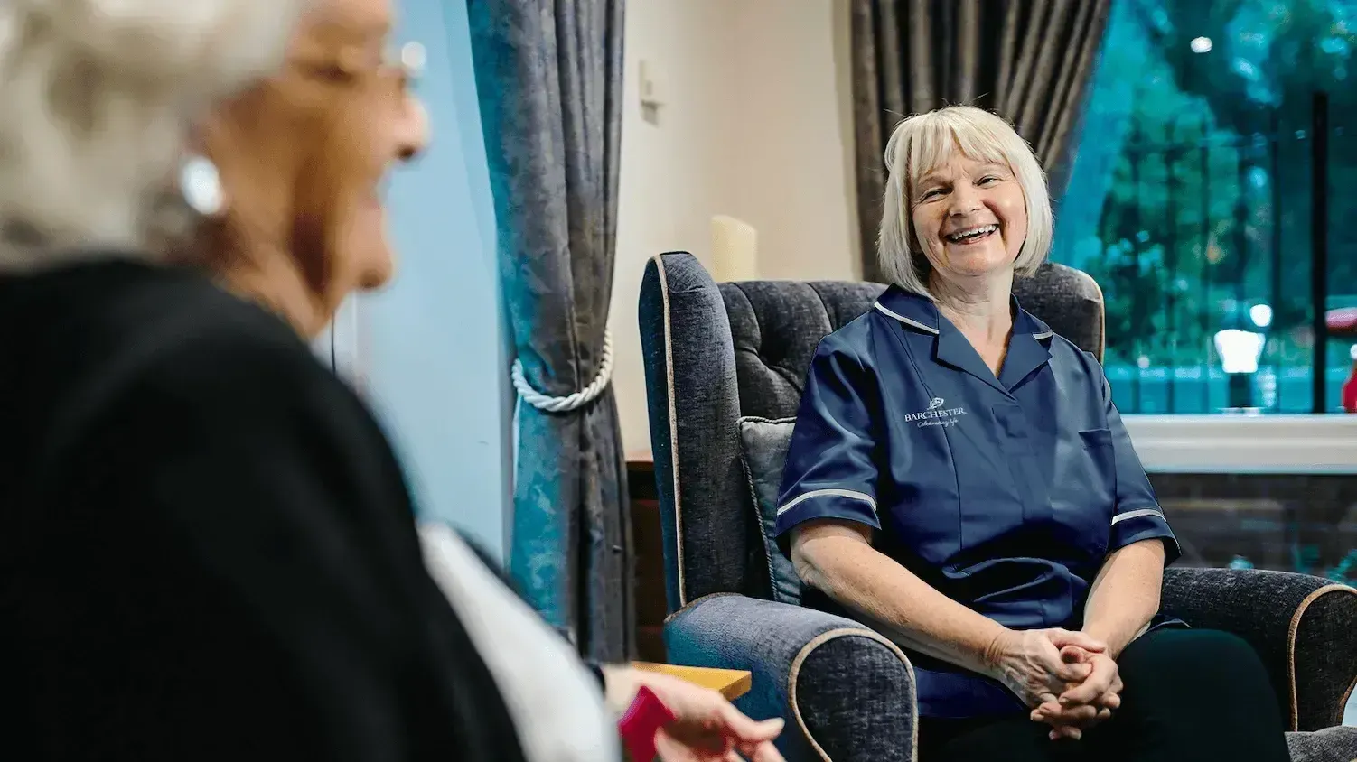 A nurse laughing with a resident 