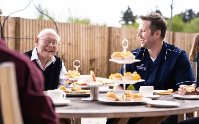 A resident and carer eating cake 
