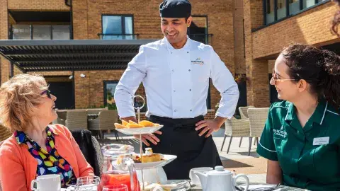 Resident, carer and chef enjoying afternoon tea in the garden